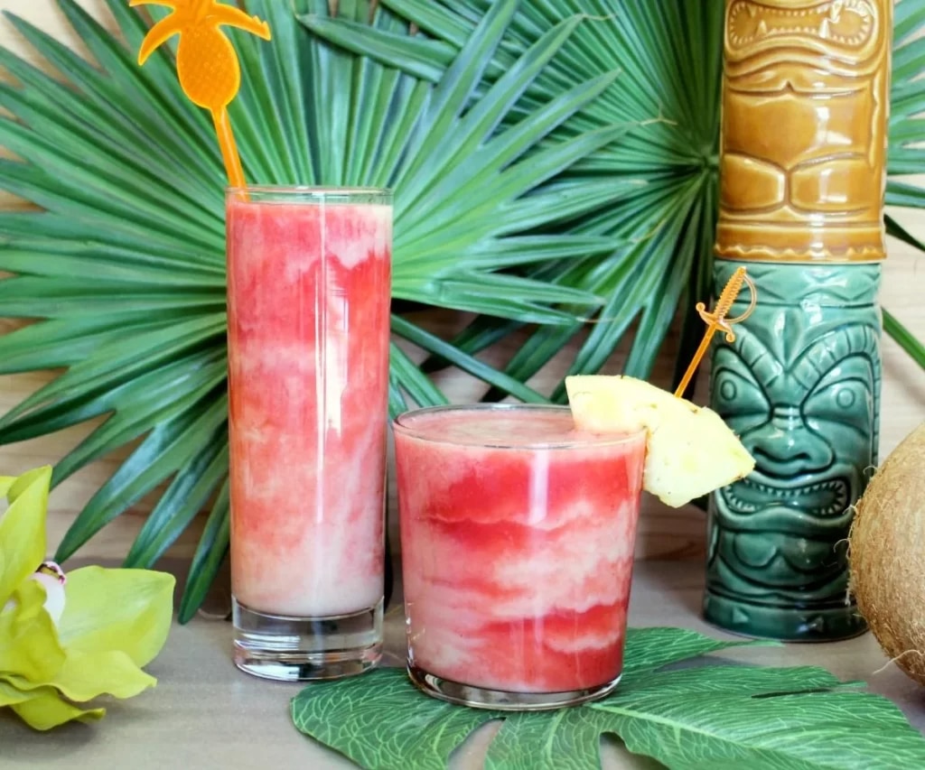 glasses of lava flow cocktail along with the leaves and coconut