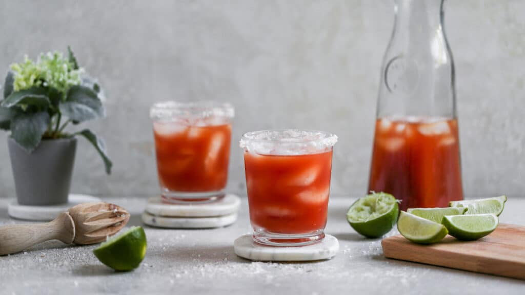 a glass of Michelada along with lime and lime squezer