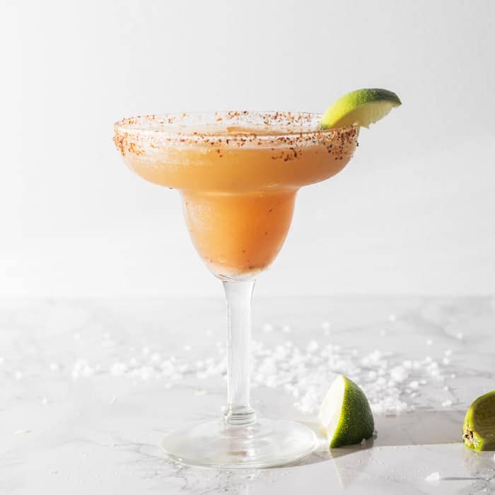 a glass of spicy tamarind margarita served with lime wedge on top