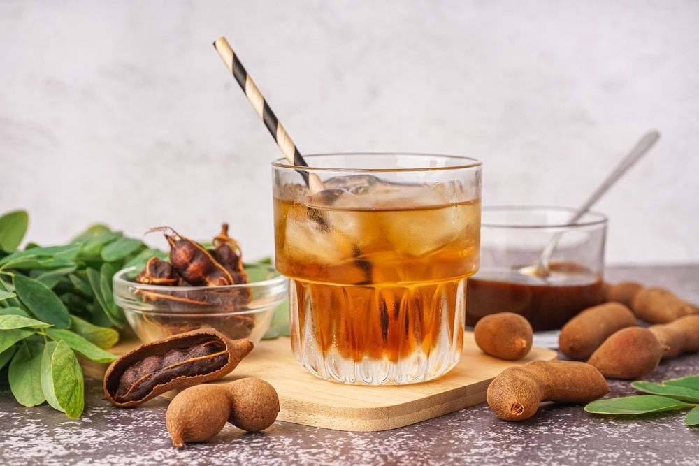 Glass Of Tasty Tamarind Drink And Fruits On Table