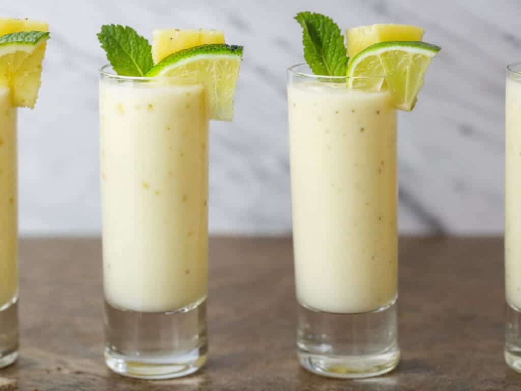 coconut cooler drink garnish with lime wedge a fresh leaf of mint and pineapple chunk