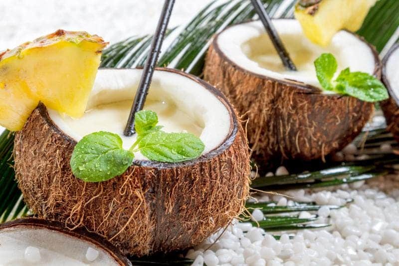 tropical orange cocobut crsuh served in the whole coconut along with pineapple chunk and mint leaves