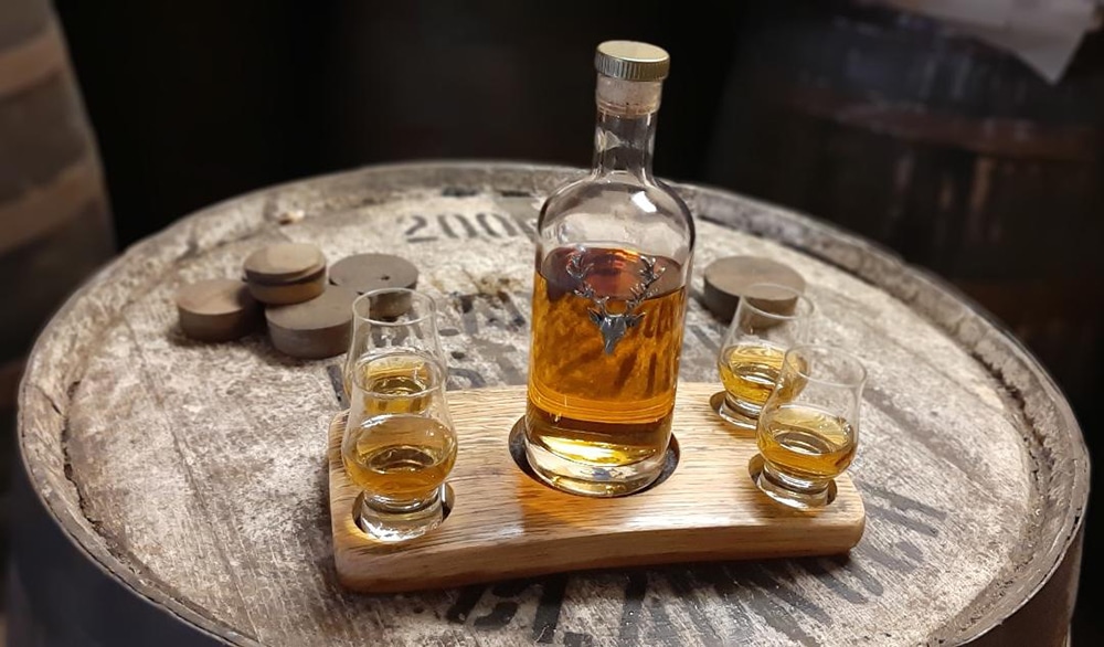 Dram of the Highlands bottle and glasses served on a wooden tray