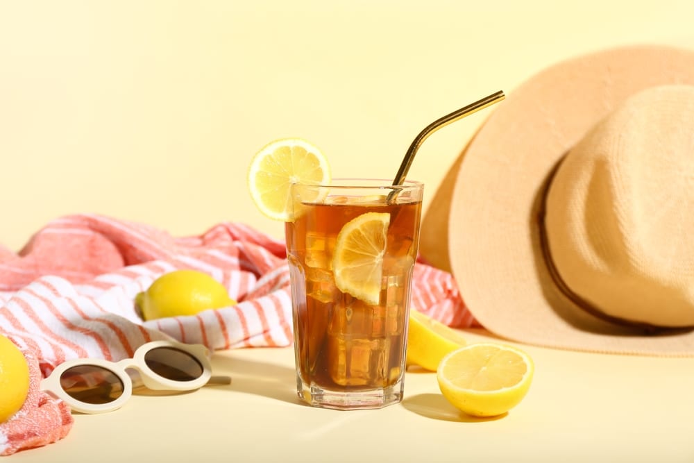 Glass Of Refreshing Long Island Iced Tea With Lemon and Sunglasses in background