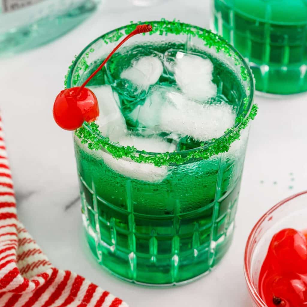 Grinch Cocktail in a glass with ice and cherry on top