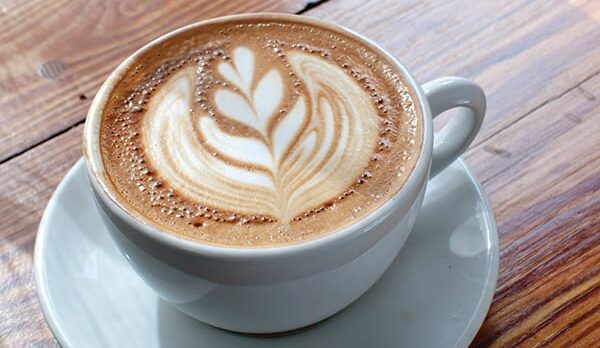 a cup of CafeauLait garnished with a floral pattern