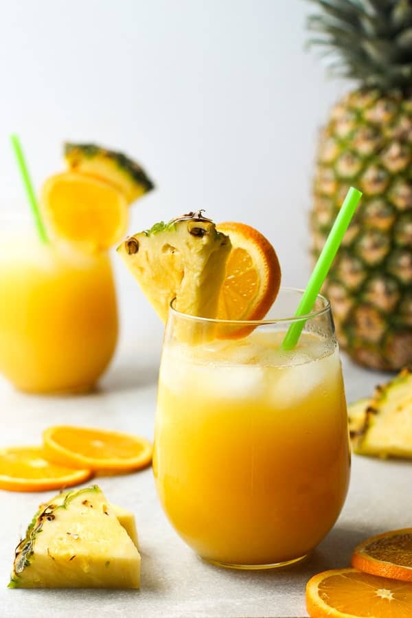 a glass of Pineapple Coconut Rum Punch garnished with pineapple wedge and orange slice