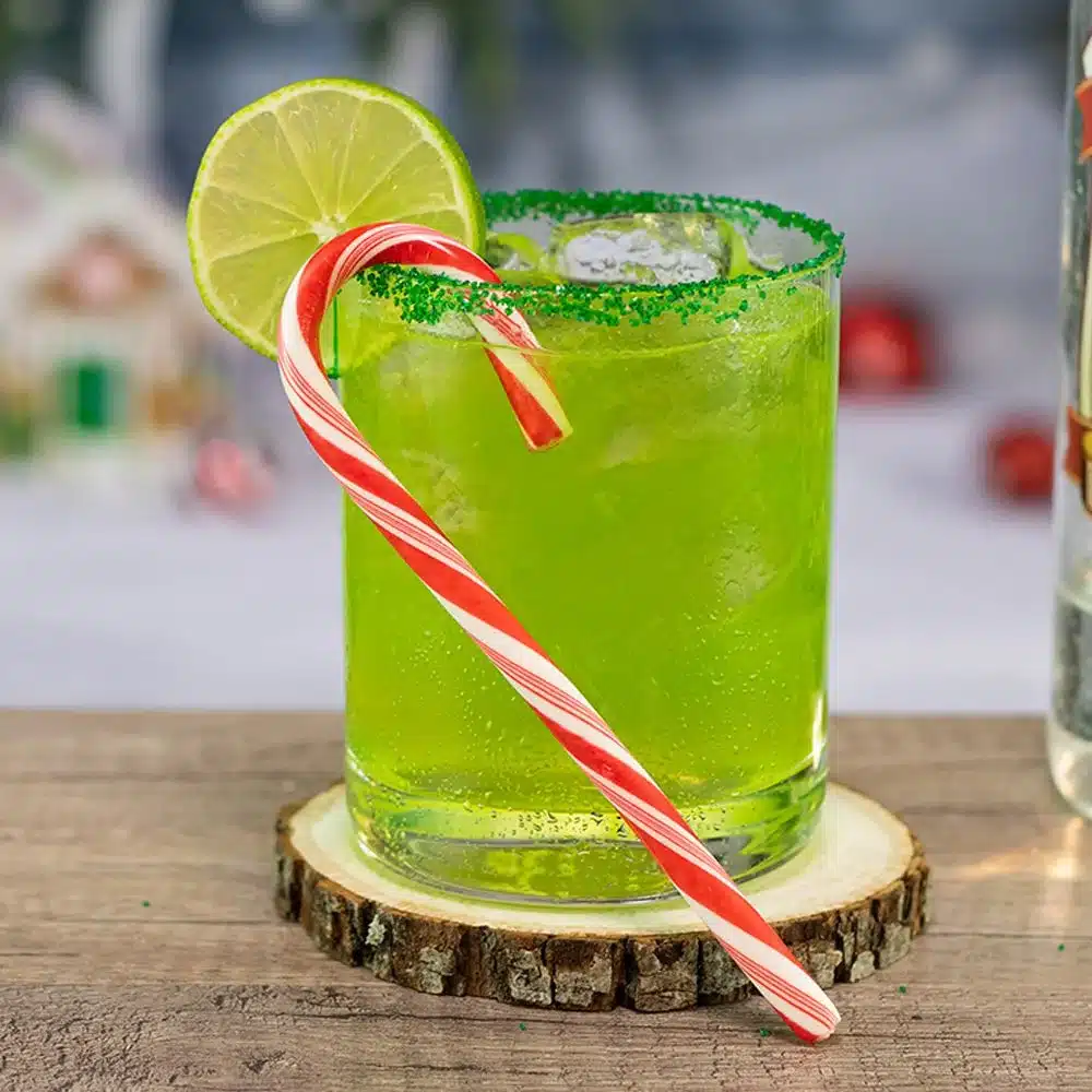 a grich drink glass in a rimmed glass with lemon wedge on top and colorful straw