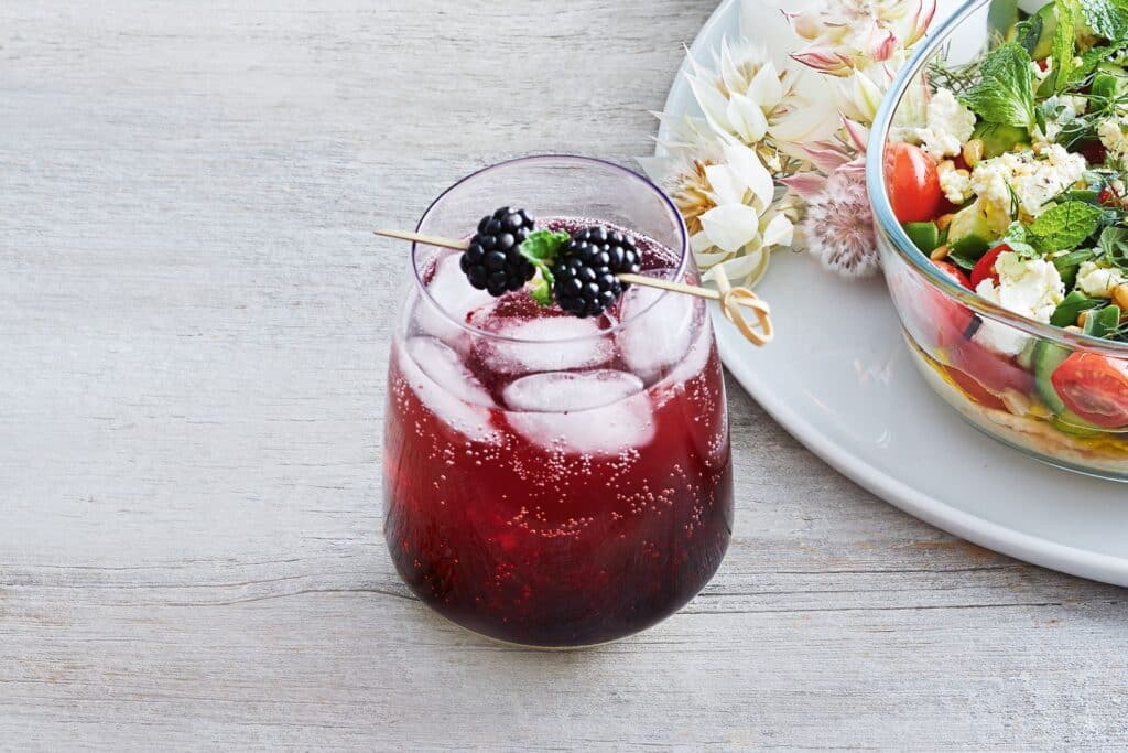 blackberry and vanilla vodka cocktail with ice and berry skewer for garnish