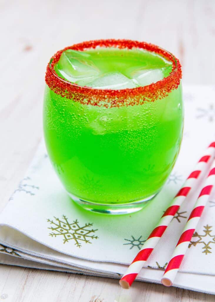 grich drink in red salt rimmed glass placed on a cloth mat with straw