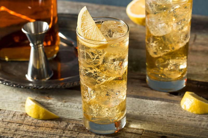 highball glass of scotch and soda garnished with lemon wedges