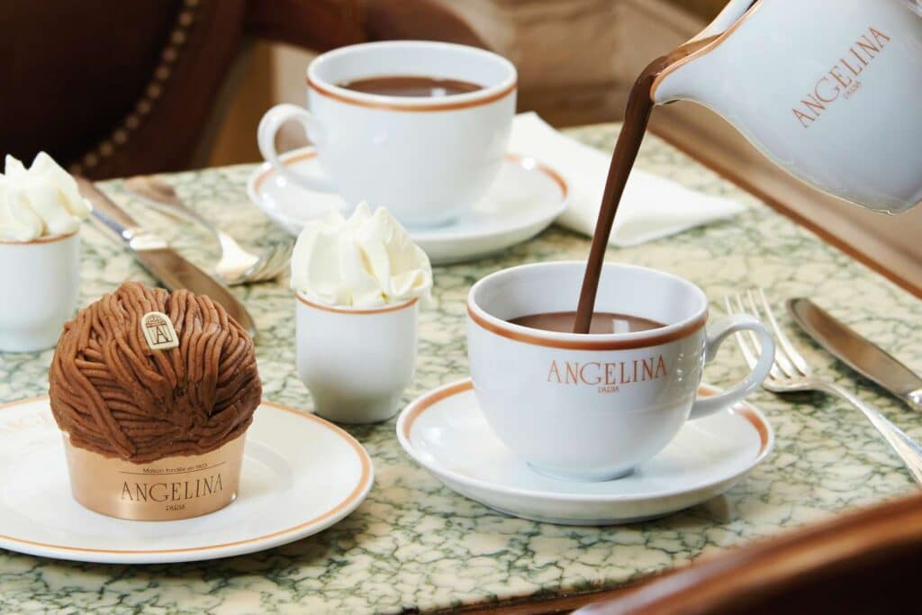 hot chocolate pouring down in a cup with a cream bowl served alongside