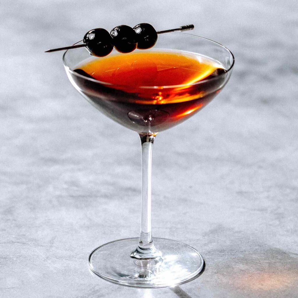 rob roy glass garnished with a skewer of berries