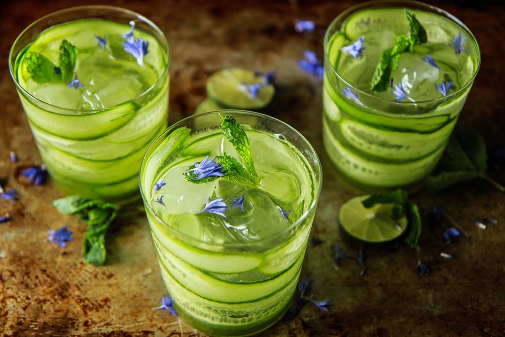 three glass of Cucumber and Mint Gin and Tonic with cucumber pieces and mint leaves for garnish