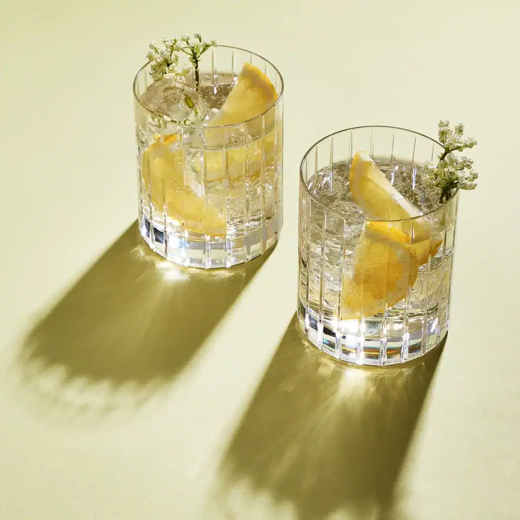 two glass of elderflower gin and tonc garnished with elderflower blossom