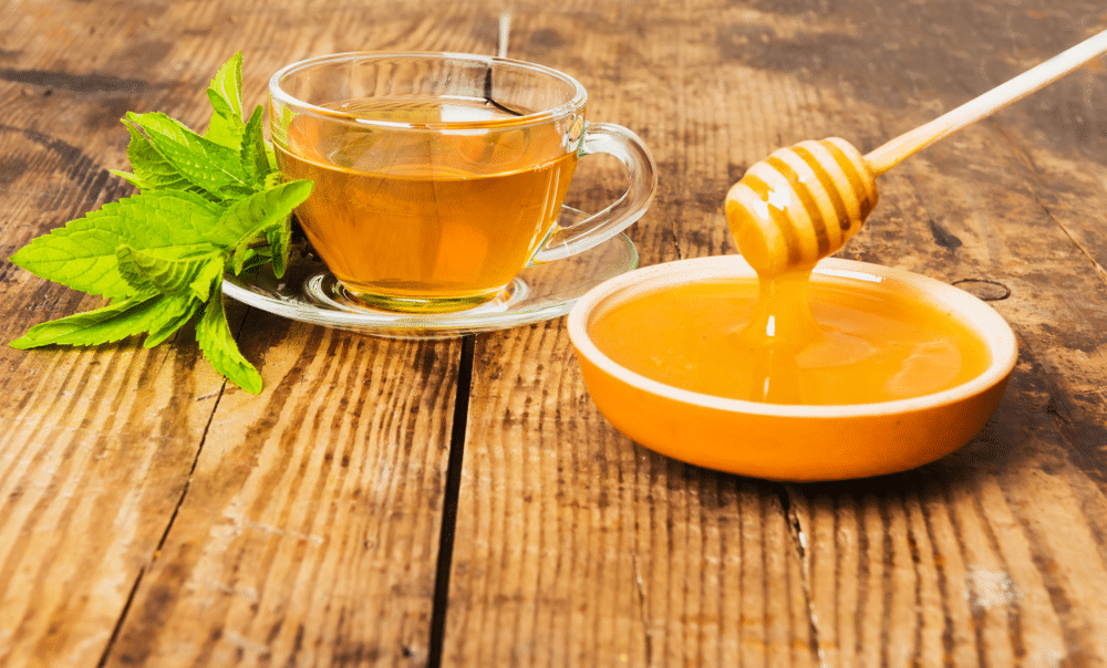 Cup of green tea mint honey on wooden background