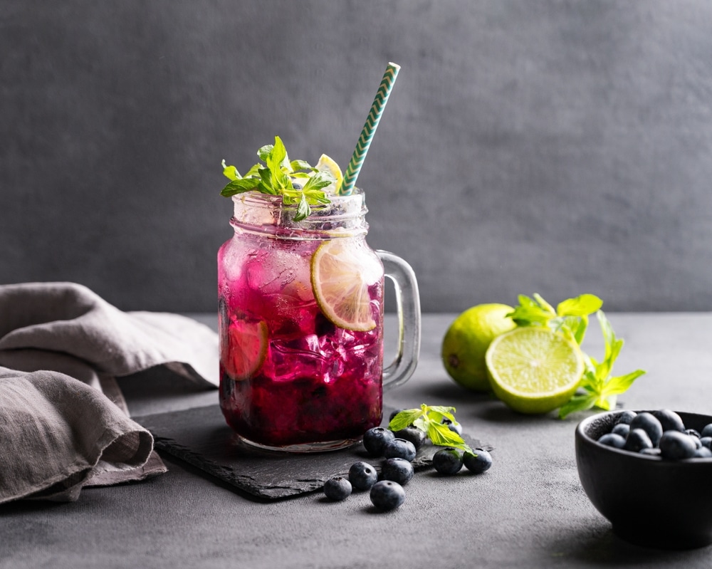 A view of a blueberry mule mojito inside a jug with lemon and blueberries