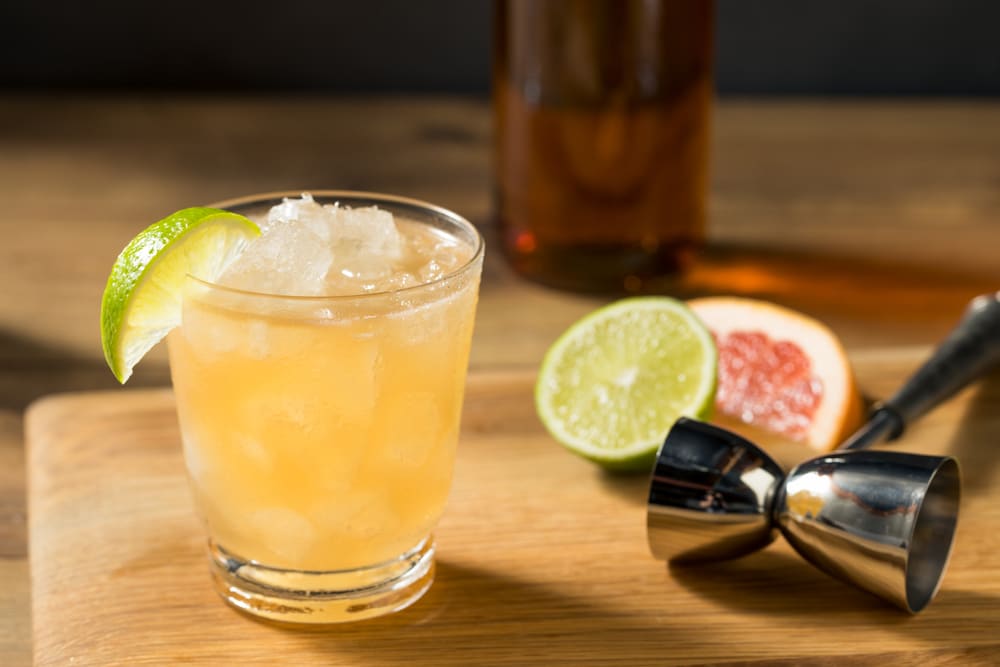 A view of a cold glass of grog cocktail with a slice of lemon on the rim