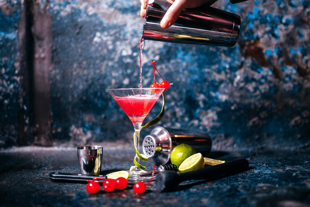 A view of a person preparing a cape cod drink with some lime and cranberries