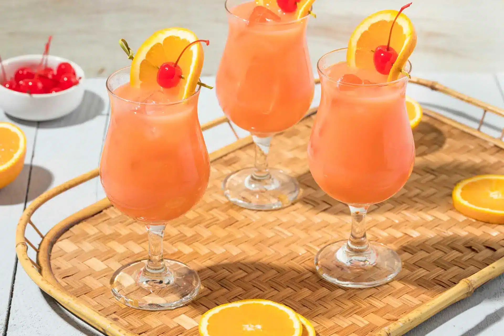 A view of three glasses of hurricane drink with oranges inside