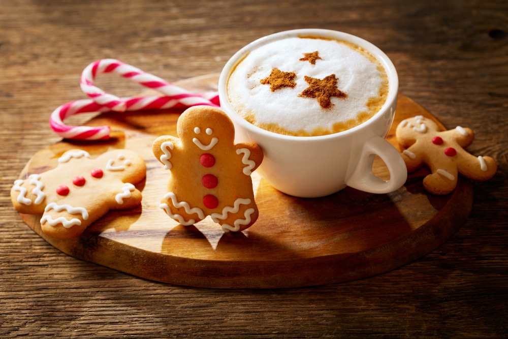 A view of a cup of gingerbread latte with gingerbread man cookies on the side