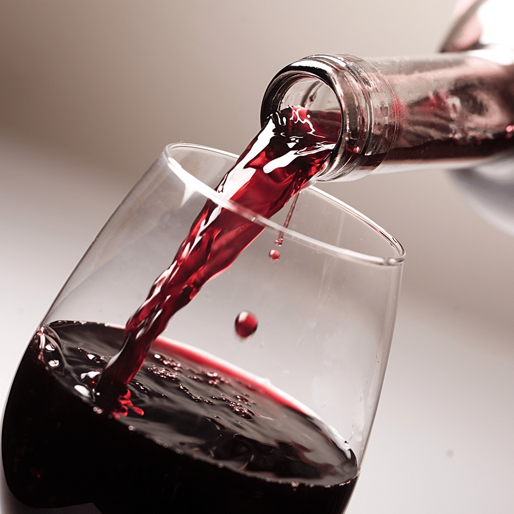 A close view of red wine being poured into a glass