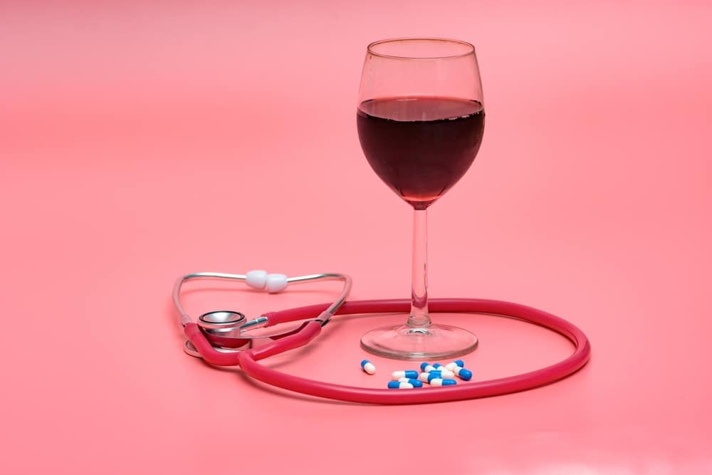 A view of a glass of red wine with diabetic pills and stethoscope