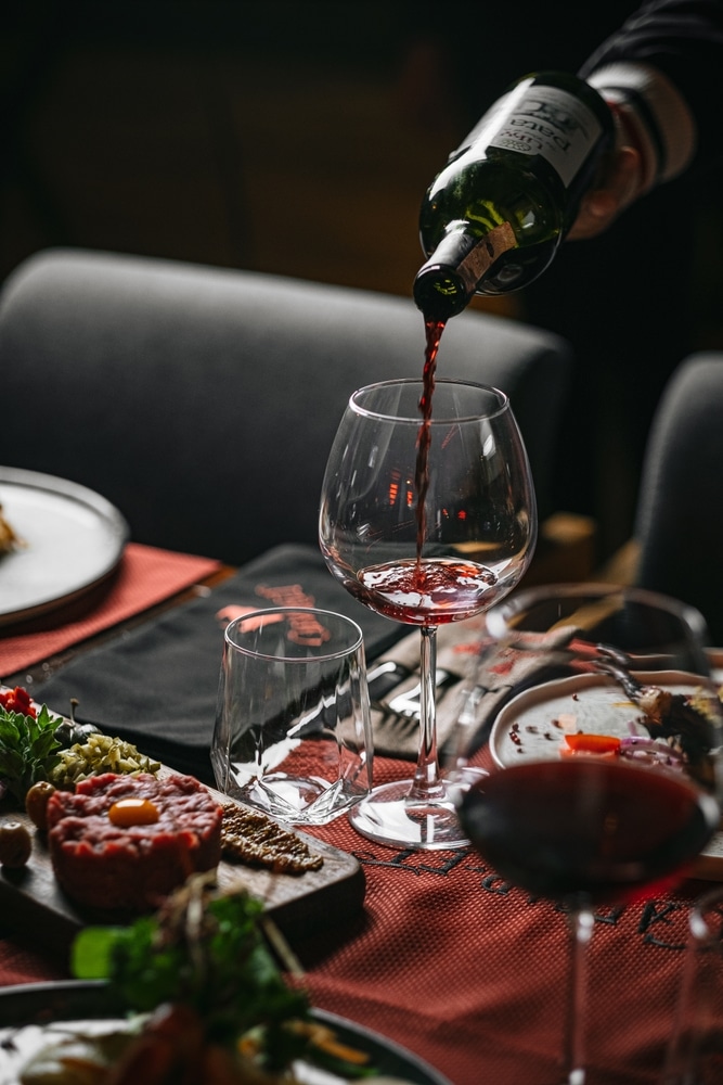 A view of red wine being poured into a glass from a bottle