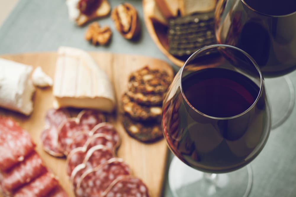 An overhead view of glasses of dry red wine beside a meal